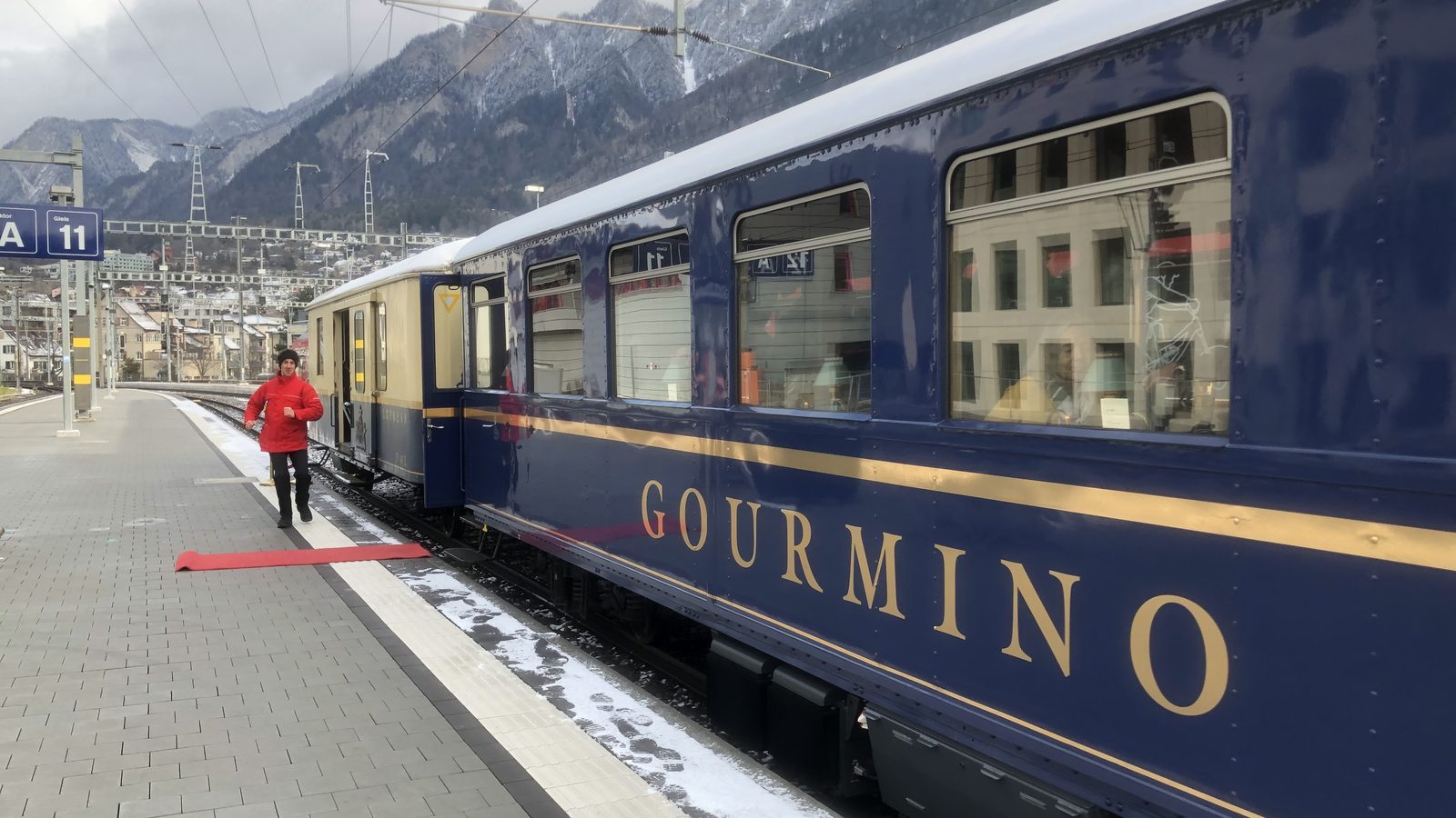Der Speisewagen Gourmino am Bahnsteig, dahinter die Bündner Berge