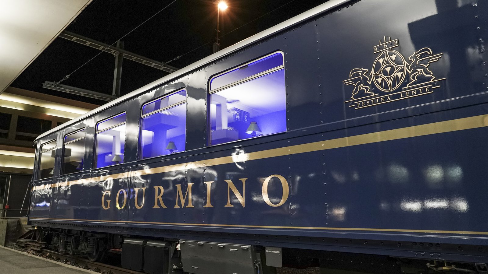 Der Speisewagen Gourmino nachts am Bahnsteig, die Fenster blau erleuchtet