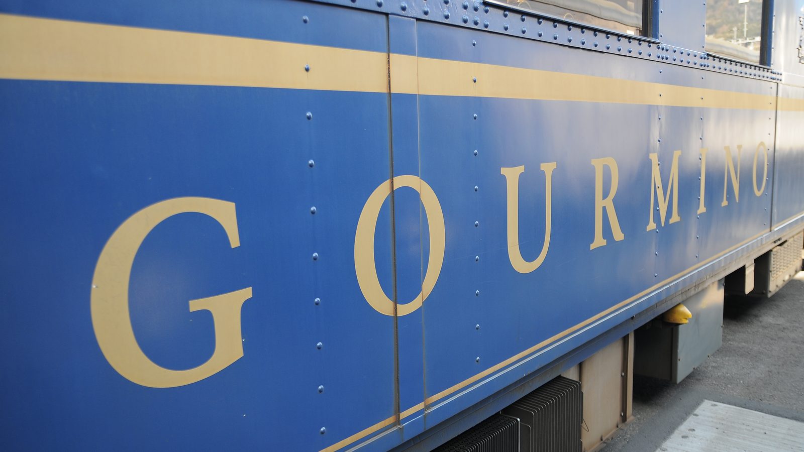 Der goldene Schriftzug GOURMINO auf der königsblauen Wagenseite, darüber ein goldener Zierstreifen