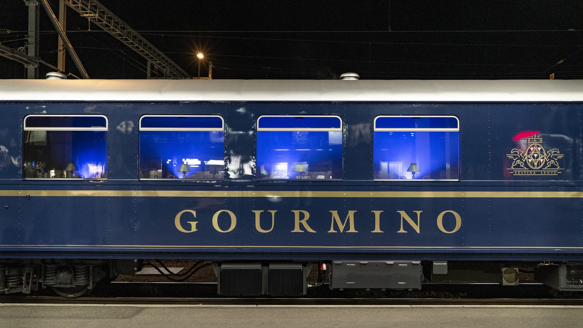 Der Speisewagen Gourmino der Rhätischen Bahn nachts am Bahnsteig, der Innenraum blau beleuchtet